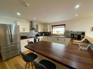 een keuken met een houten tafel en een koelkast bij Teaghlach, Cairngorms - Escape Cottages Scotland in Newtonmore