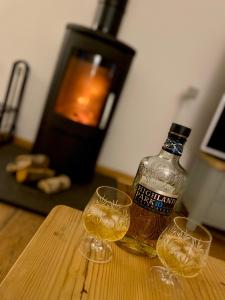 een fles whisky en twee wijnglazen op een tafel bij Teaghlach, Cairngorms - Escape Cottages Scotland in Newtonmore