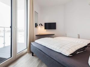 een slaapkamer met een bed en een balkon met een televisie bij Apartment Wendtorf III in Wendtorf