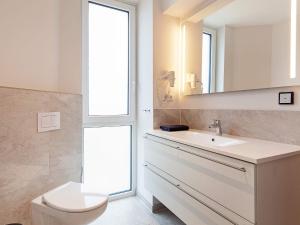 ein Badezimmer mit Toilette, Waschbecken und Spiegel in der Unterkunft 6 Personen Ferienhaus in Wendtorf in Wendtorf + 45 Fotos