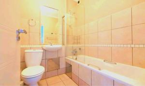 a bathroom with a toilet and a sink and a tub at Beachside 3 bed apartment with stunning seaviews in Amanzimtoti +16 photos