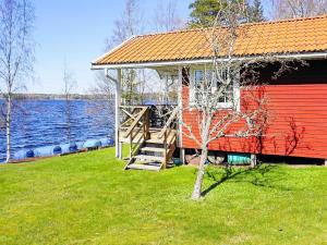 una casa roja al lado de un cuerpo de agua en 6 person holiday home in GULLSP NG en Gullspång