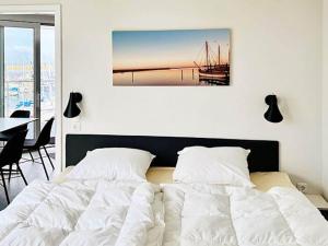 a bedroom with a bed with a picture on the wall at Moderne Wohnung mit direktem Meerblick in Wendtorf