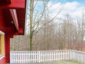 une véranda d'une maison rouge avec une clôture blanche dans l'établissement 4 person holiday home in HJ RNARP, à Hjärnarp