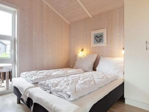 Bett mit weißer Bettwäsche und Kissen in einem Zimmer in der Unterkunft Two-Bedroom Holiday home in Grömitz 1 in Grömitz