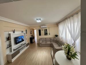 a living room with a couch and a tv at Apartamento pé na areia Balneário Camboriú! Av. Atlântica. in Balneário Camboriú