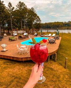 a person holding up a red drink with berries on it at Tedesco Eco Park in São Francisco de Paula