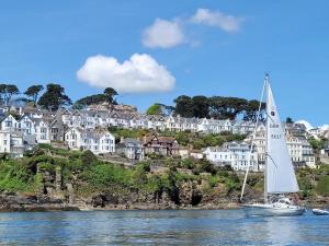 a sailboat in the water in front of houses at The Wheelhouse in Fowey