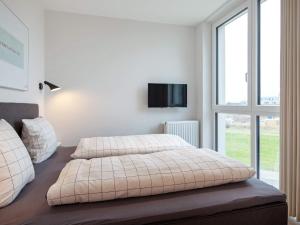 a bedroom with a bed and a tv on the wall at Apartment Wendtorf VII in Wendtorf