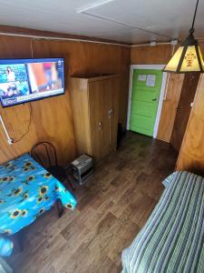 a room with a bed and a tv on the wall at Hostal y Cabañas Maribel Zuñiga in Valdivia
