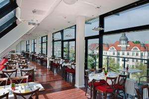 um restaurante com mesas e cadeiras e janelas grandes em Come Inn Berlin Kurfürstendamm em Berlim
