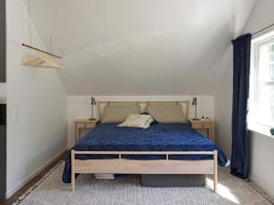 a bedroom with a bed with a blue comforter and a window at Holiday home RIMBO II in Rimbo