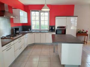 una cocina con armarios blancos y una pared roja en Breton cottage in a quiet location with fireplace, Plouenan en Plouénan