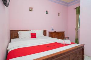 a bedroom with a bed with a red blanket on it at RedDoorz Syariah near Batu Night Spectacular 3 in Batu