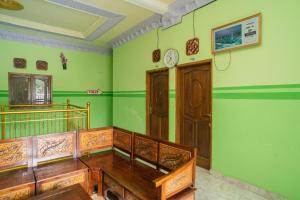 Pokój z zielonymi ścianami, drewnianymi meblami i zegarem w obiekcie RedDoorz Syariah near Batu Night Spectacular 3 w mieście Batu
