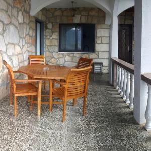 einen Holztisch und Stühle vor einer Steinmauer in der Unterkunft Apartments MILA in Ubli