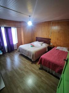 1 dormitorio con 2 camas y suelo de madera en Hostal y Cabañas Maribel Zuñiga en Valdivia