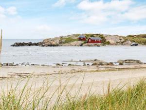 uma casa vermelha numa pequena ilha no oceano em 4 person holiday home in Heberg em Heberg