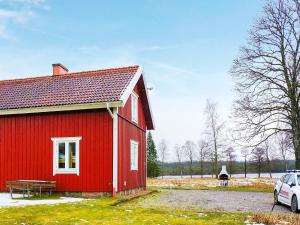 a red house with a car parked next to it at 8 person holiday home in LJUNG in Ljung