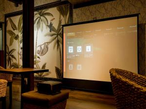 a projection screen in a room with a table and chairs at 癒楽 伊豆大島 in Oshima