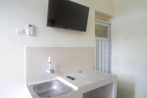 a bathroom with a sink with a tv on the wall at RedDoorz Syariah near Universitas Slamet Riyadi Solo in Karanganyar +19 photos