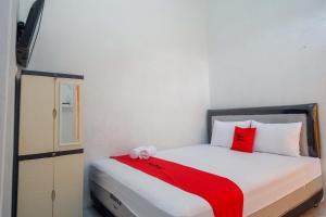 a small bedroom with a bed with a red blanket at RedDoorz Syariah near Universitas Slamet Riyadi Solo in Karanganyar