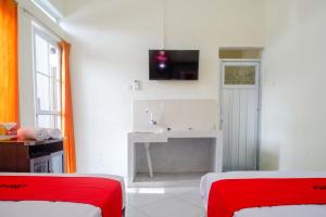 a room with two beds and a sink and a tv at RedDoorz Syariah near Universitas Slamet Riyadi Solo in Karanganyar