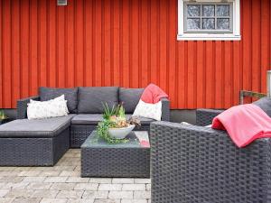 un patio con muebles de mimbre y una pared roja en 5 person holiday home in LINDOME SVERIGE 