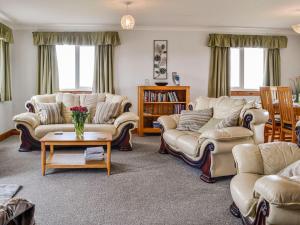 a living room with couches and a table at Auld Dairy Cottage in Drummore