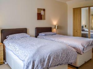 a bedroom with two beds and a mirror at Auld Dairy Cottage in Drummore