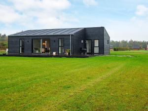 ein kleines schwarzes Haus auf einem Grasfeld in der Unterkunft 8 person holiday home in Ansager in Ansager