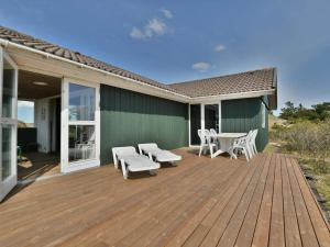 una terraza de madera con sillas y mesas en una casa en 6 person holiday home in Fanø-By Traum, en Fanø