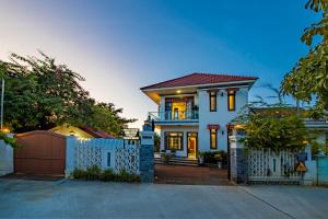 une maison blanche avec un portail et une clôture dans l'établissement Sông River Homestay Hội An, à Hội An
