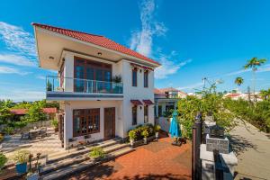 une maison blanche avec un toit rouge dans l'établissement Sông River Homestay Hội An, à Hội An