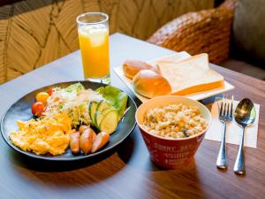 een tafel met een bord eten en een glas sinaasappelsap bij 癒楽 伊豆大島 in Oshima