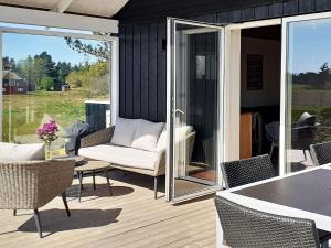 een afgeschermde veranda met een bank en een tafel en stoelen bij 5 person holiday home in R m in Kongsmark