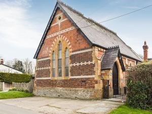 una antigua iglesia de ladrillo rojo con techo negro en The Sunday Schoolroom en Wootton Glanville