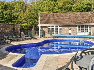 a swimming pool with chairs and a house at Rabbits Warren in Trelaske