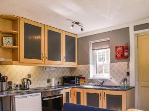 a kitchen with wooden cabinets and a microwave at Rabbits Warren in Trelaske