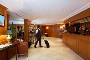 a man walking through a hotel lobby with a suitcase at Hôtel Horset Opéra, Best Western Premier Collection in Paris