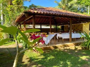 a pavilion with a table and chairs in a garden at Pousada Refugium in Itacaré