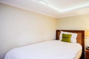 a bedroom with a white bed with a green pillow at Urbanview Rumah Kandjani Yogyakarta in Yogyakarta