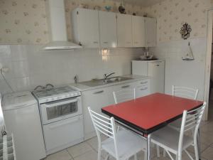a kitchen with a red table and white appliances at La maison du Barbot Maison 6 couchages in Gujan-Mestras