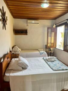 1 dormitorio con 2 camas y ventana en Pousada Refugium, en Itacaré
