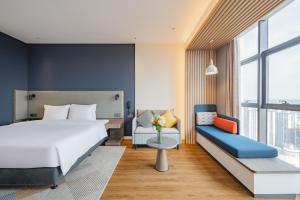 南寧市にあるHoliday Inn Express Nanning Jiangnan, an IHG Hotelのベッドルーム(大きな白いベッド1台、ソファ付)