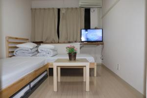 東京にあるSophiearth Apartment のベッド2台、テレビ、テーブルが備わる客室です。