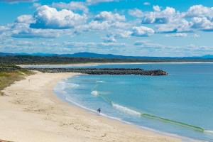 a person riding a wave on a beach at El Sandi 12 in Forster +4 photos
