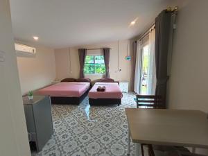 una camera d'albergo con due letti e una finestra di บ้านในสวนรีสอร์ทBannnaisuan Resort a Prachuap Khiri Khan