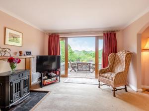 a living room with a television and a chair at Cwmfron House in Llanidloes