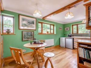 a kitchen with green walls and a table and chairs at Cwmfron House in Llanidloes